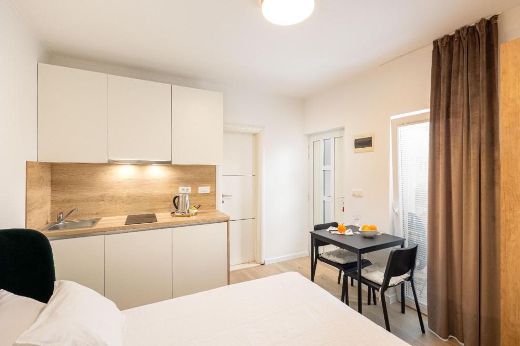 a room with a bed and a kitchen and a table at Apartments & Rooms Buble in Trogir