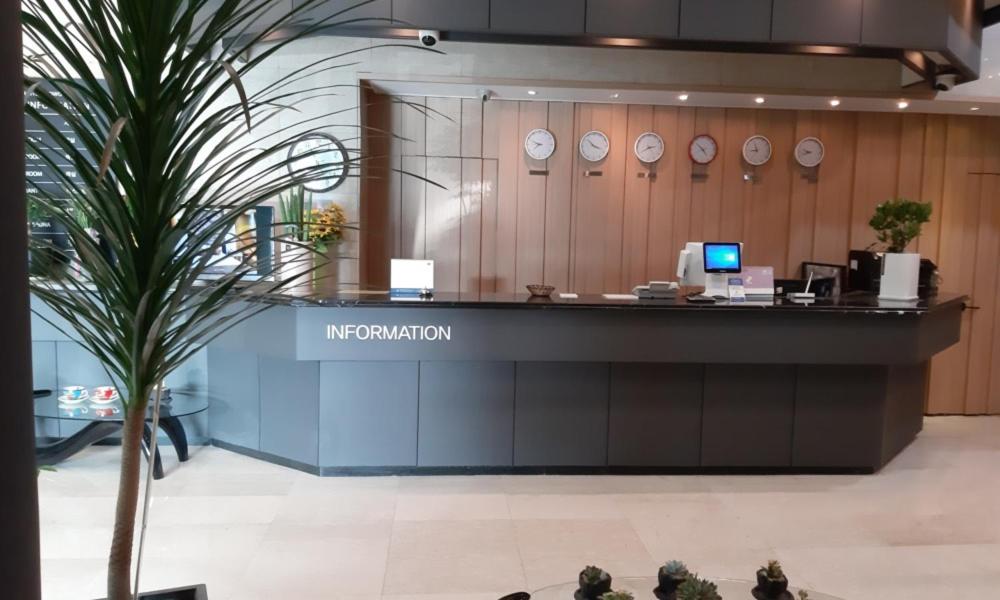 a lobby with a counter with clocks on the wall at Ansan Seowon Tourist Hotel in Ansan