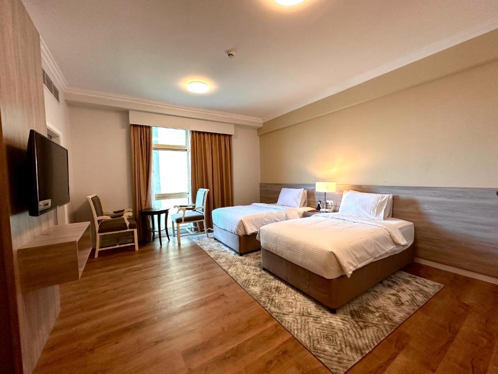 a hotel room with two beds and a flat screen tv at MIRADOR HOTEL in Manama