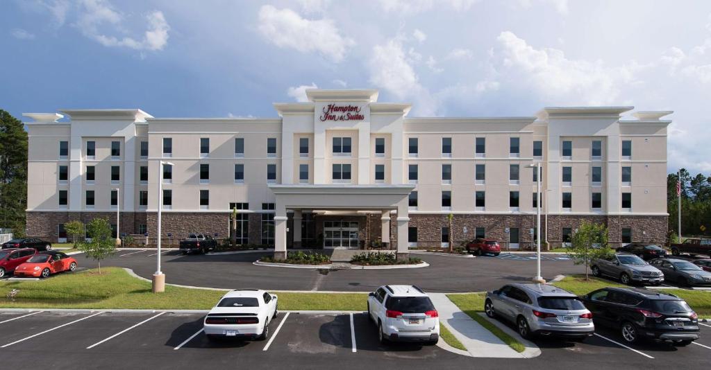 een groot wit gebouw met auto's geparkeerd op een parkeerplaats bij Hampton Inn and Suites Fayetteville, NC in Fayetteville