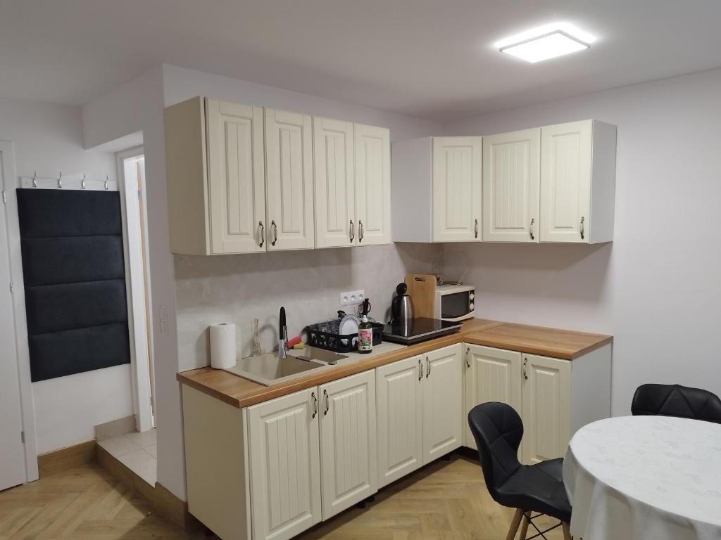 uma cozinha com armários brancos e uma mesa em Piasecki Apartamenty em Lublin