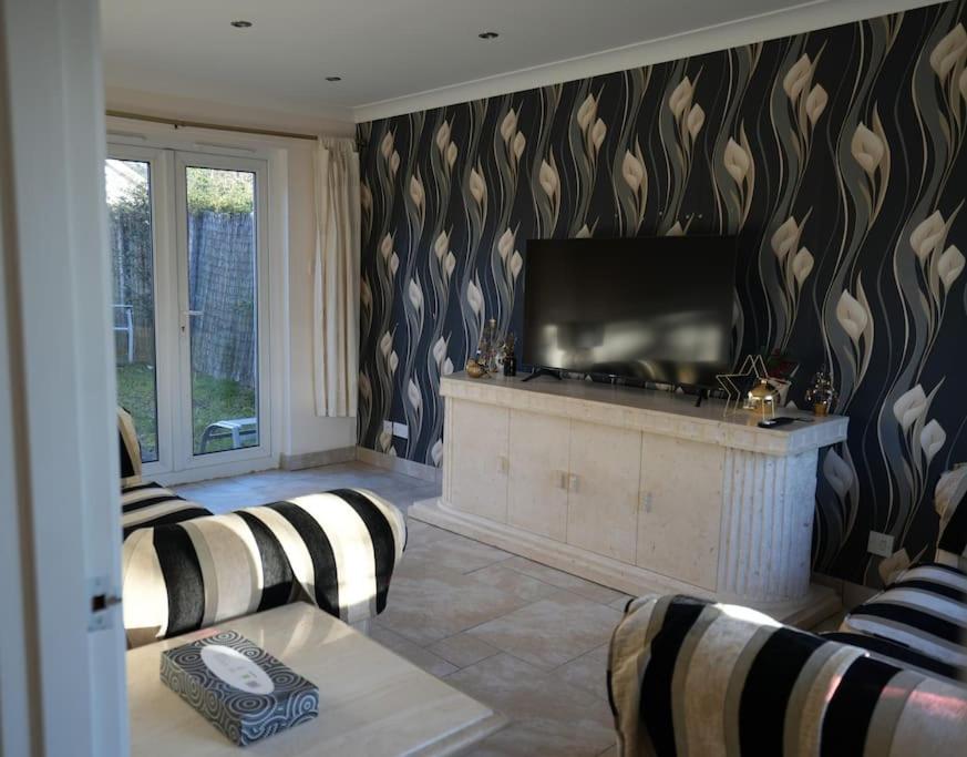 a living room with a flat screen tv on a wall at Cosy Stirling 3-bedroom Home in Stirling