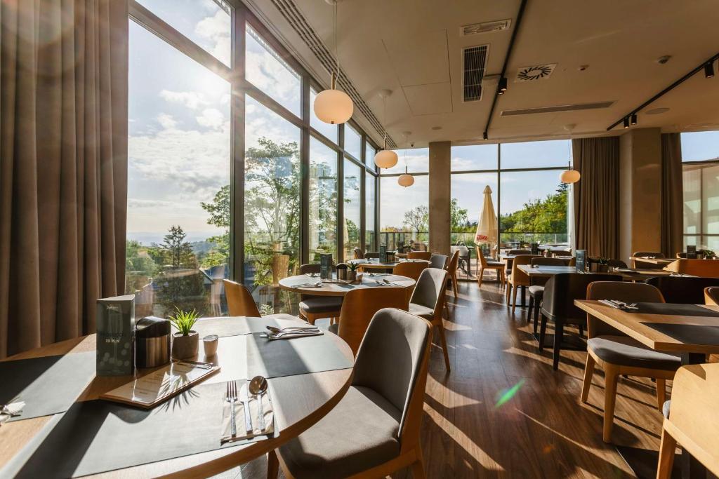 een restaurant met tafels en stoelen en grote ramen bij Radisson Hotel Szklarska Poręba in Szklarska Poręba