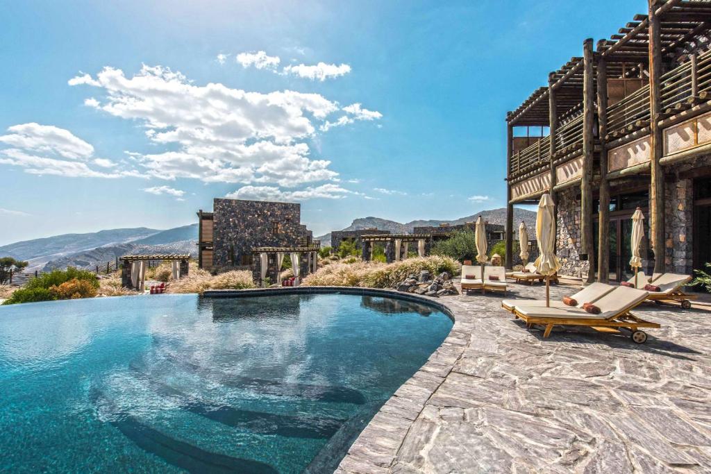 a swimming pool in front of a house with mountains at Alila Jabal Akhdar in Al Khuţaym