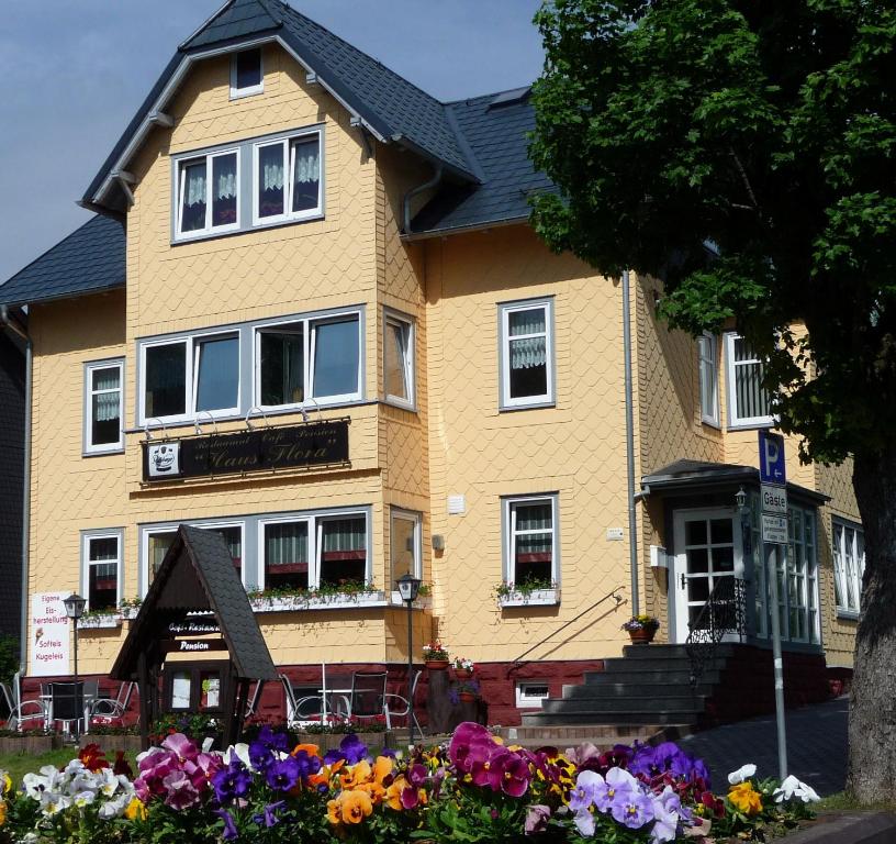ein gelbes Haus mit Blumen davor in der Unterkunft Pension Haus Flora in Oberhof