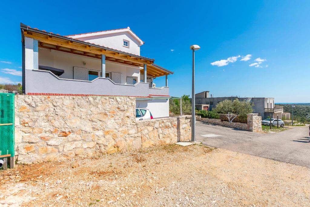 a house with a stone wall next to a street at Apartments Barica in Primošten