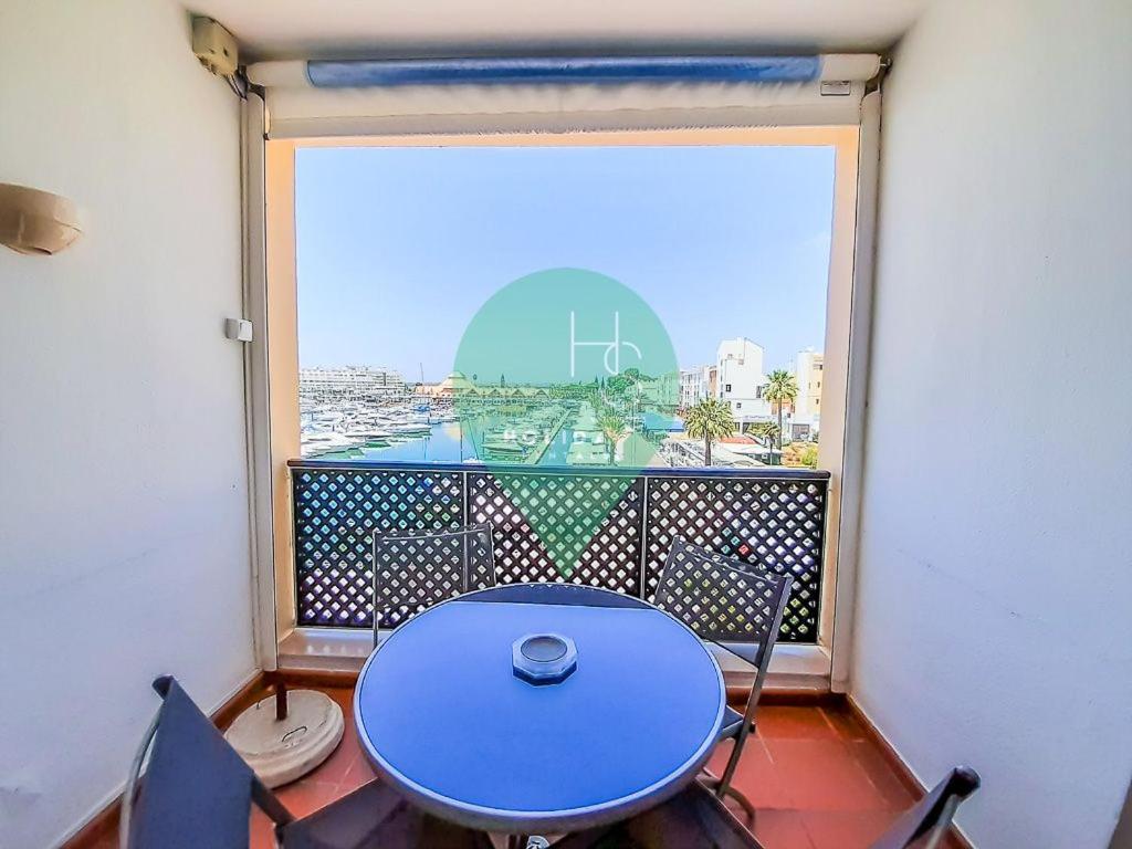 una mesa azul y sillas en un balcón con ventana en Penthouse Duplex Vista Marina T1 Ap por HsRentals en Vilamoura