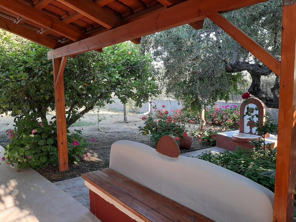 a wooden pergola with a bench in a garden at Spiti Xenia in Ierapetra