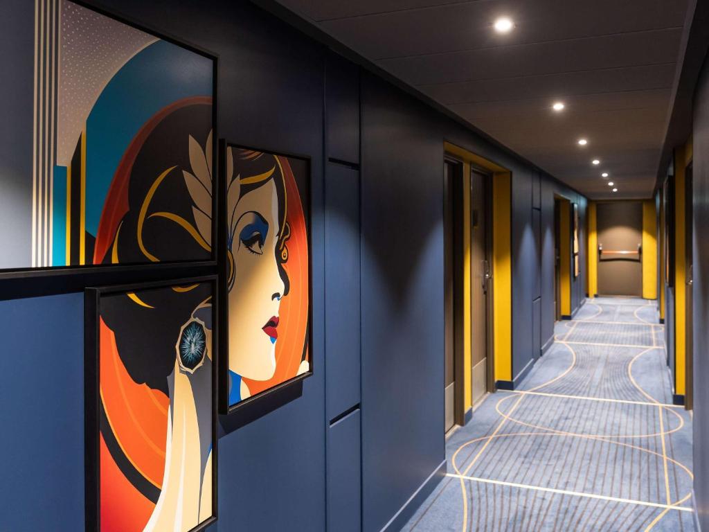a hallway with paintings of a woman on the wall at ibis Styles Saint-Quentin in Saint-Quentin