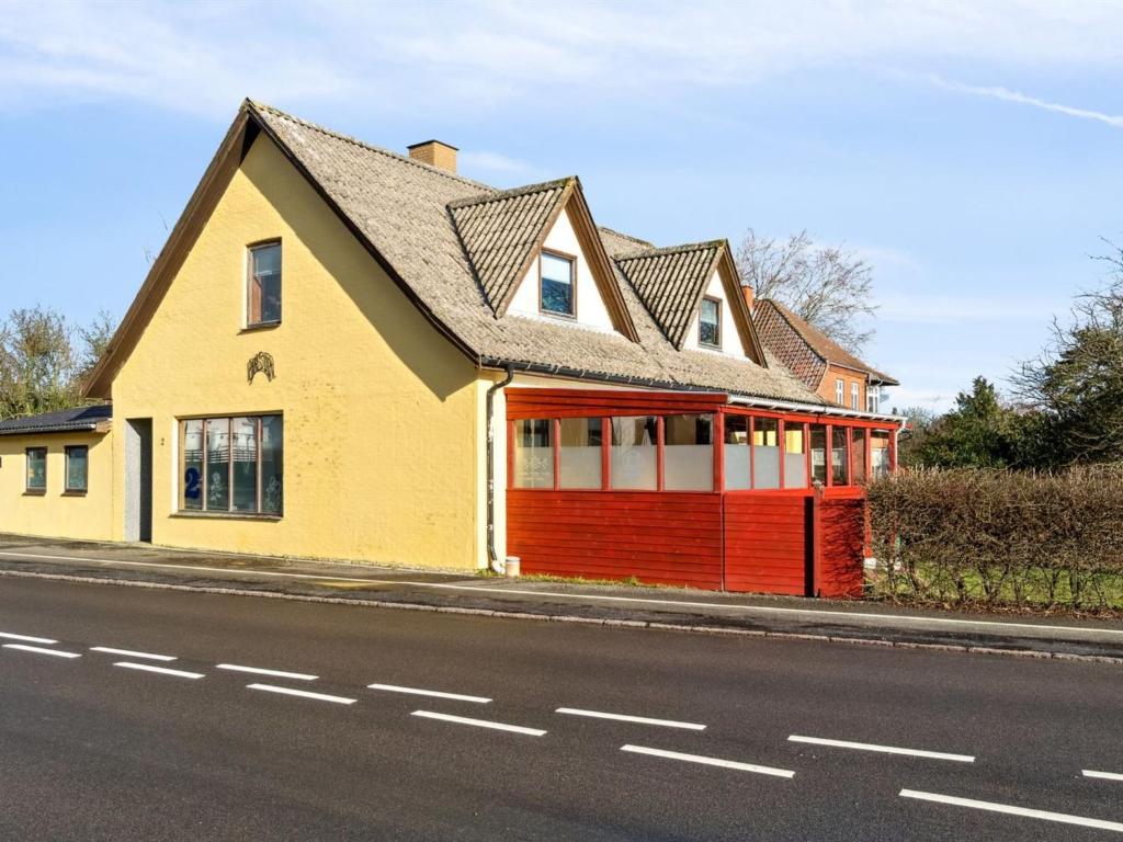 a yellow and red house on the side of a street at Apartment Thera - 5km from the sea in Bornholm by Interhome in Gudhjem