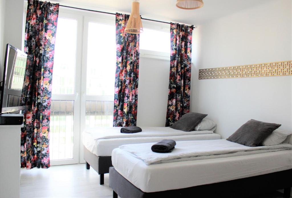 duas camas num quarto com janelas e cortinas em Labo Apartment Graniczna em Varsóvia