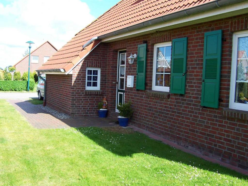 una casa in mattoni rossi con persiane verdi e un cortile di Ferienwohnungen Höhn ad Altfunnixsiel