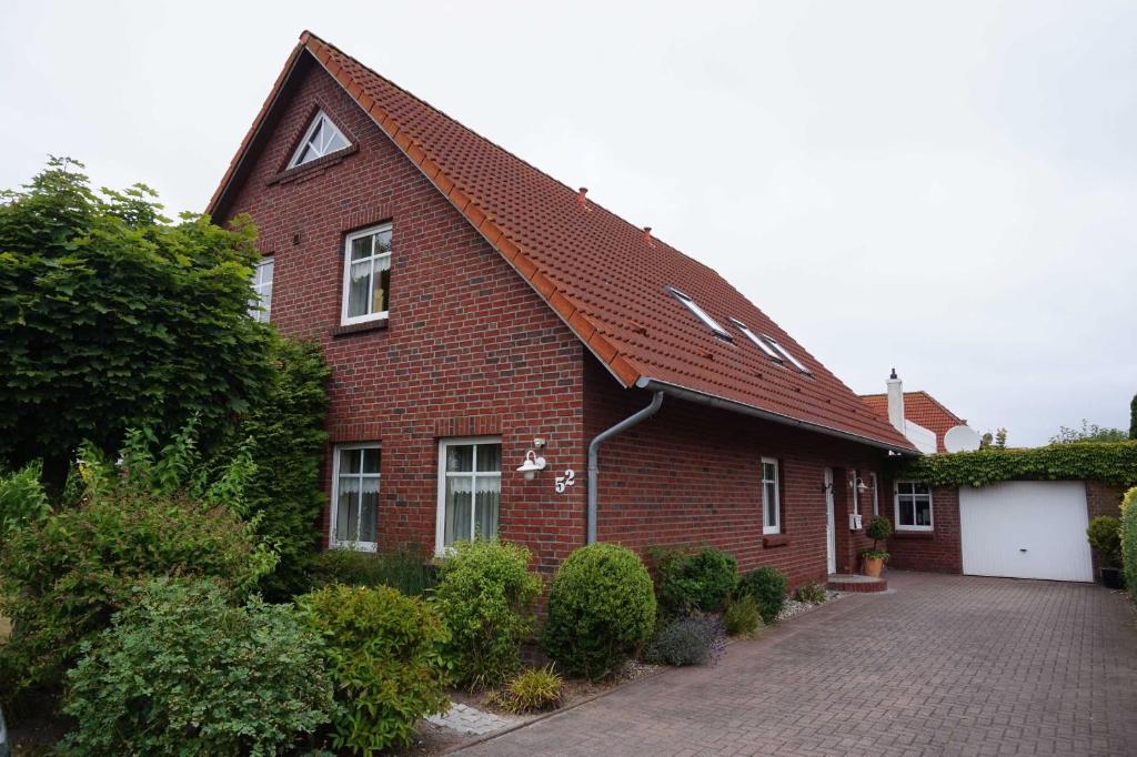 a brick house with a red roof and a driveway at Ferienwohnungen Tovar in Carolinensiel