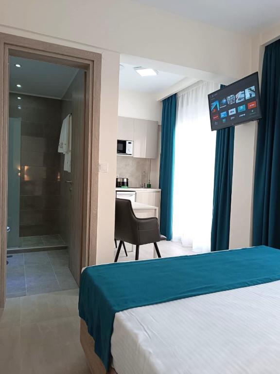 a bedroom with a bed and a chair and a kitchen at Navarino Luxe Suites in Perea