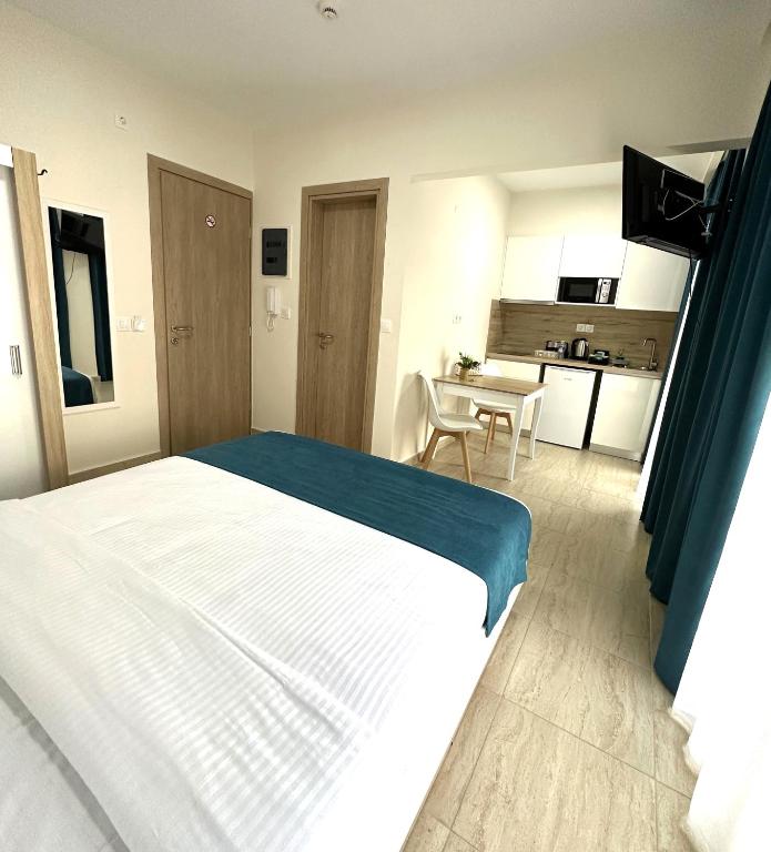 a bedroom with a white bed and a kitchen at Navarino Luxe Suites in Perea