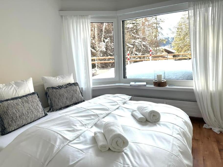 um quarto com uma grande cama branca com toalhas em Wonderful cosy apartment in St. Moritz em St. Moritz
