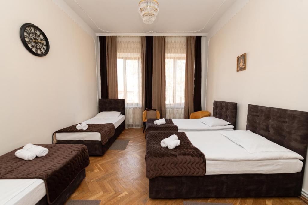 een kamer met drie bedden en een klok aan de muur bij Anna's Guest House in Gori