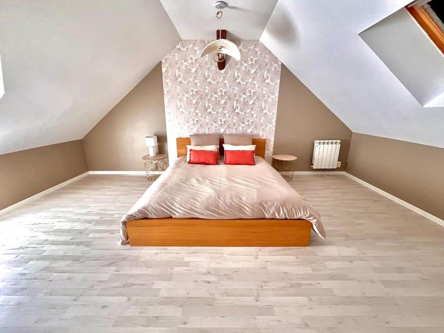 a bedroom with a large bed with red pillows at La maison de Paulette in Onzain