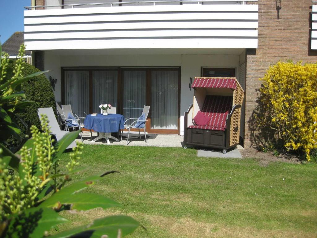 a backyard with a table and chairs and a grill at Ferienwohnung Goldan Möwenweg in Carolinensiel