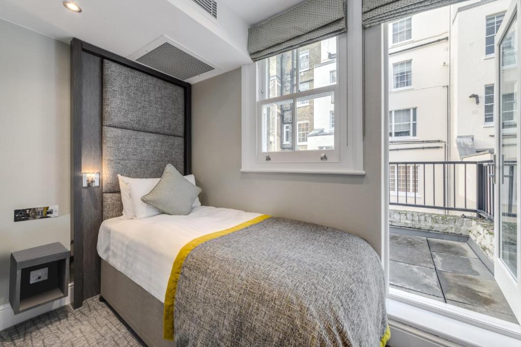 a bedroom with a bed and a large window at Mornington Hotel London Victoria in London
