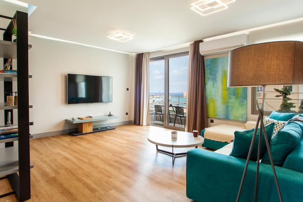 un soggiorno con divano blu e TV di Minimal Loft Art with Sea View Over Heraklion Harbour a Heraklion