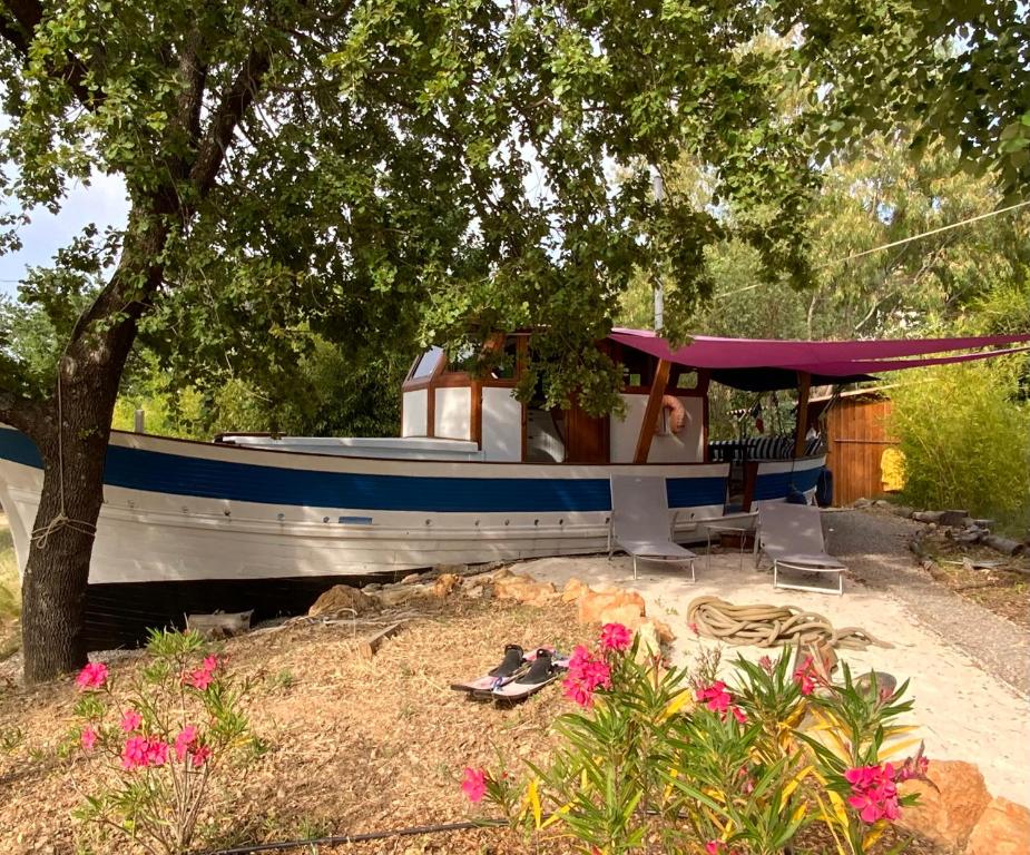 un bateau bleu et blanc garé sous un arbre dans l'établissement GÉRARD L’HERMITE, à Figanières