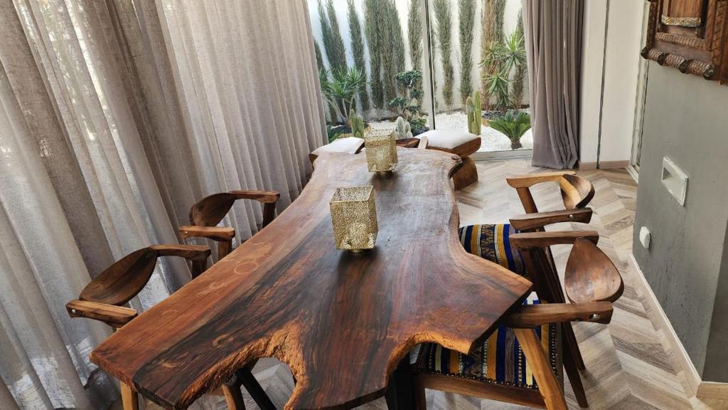a wooden table in a living room with chairs at Studio Haut standing Casa finance City Tour Vegetale Yasmine Signature Résidence in Casablanca