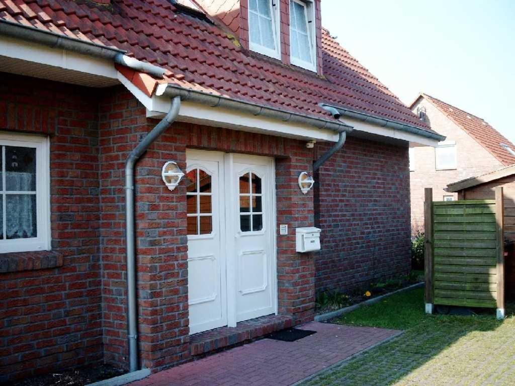 uma casa de tijolos vermelhos com uma porta branca em Ferienwohnung Schwalbennest em Carolinensiel