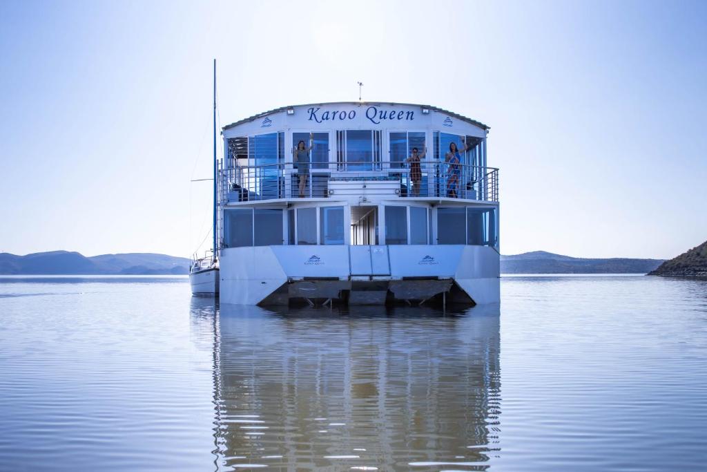 a ferry boat is sitting on the water at Karoo Queen Houseboat, Gariepdam in Gariepdam