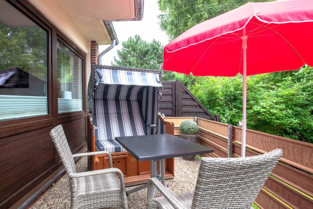 a patio with a table and chairs and an umbrella at Wiesenglück in Wyk auf Föhr