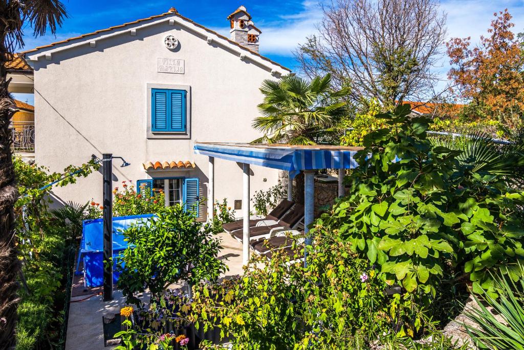 a house with a blue awning and plants at Holiday house Villa Marija, Pinezici in Krk