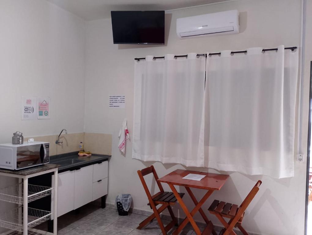 a kitchen with a table and two chairs and a microwave at Pousada Ebenezer in Andradina