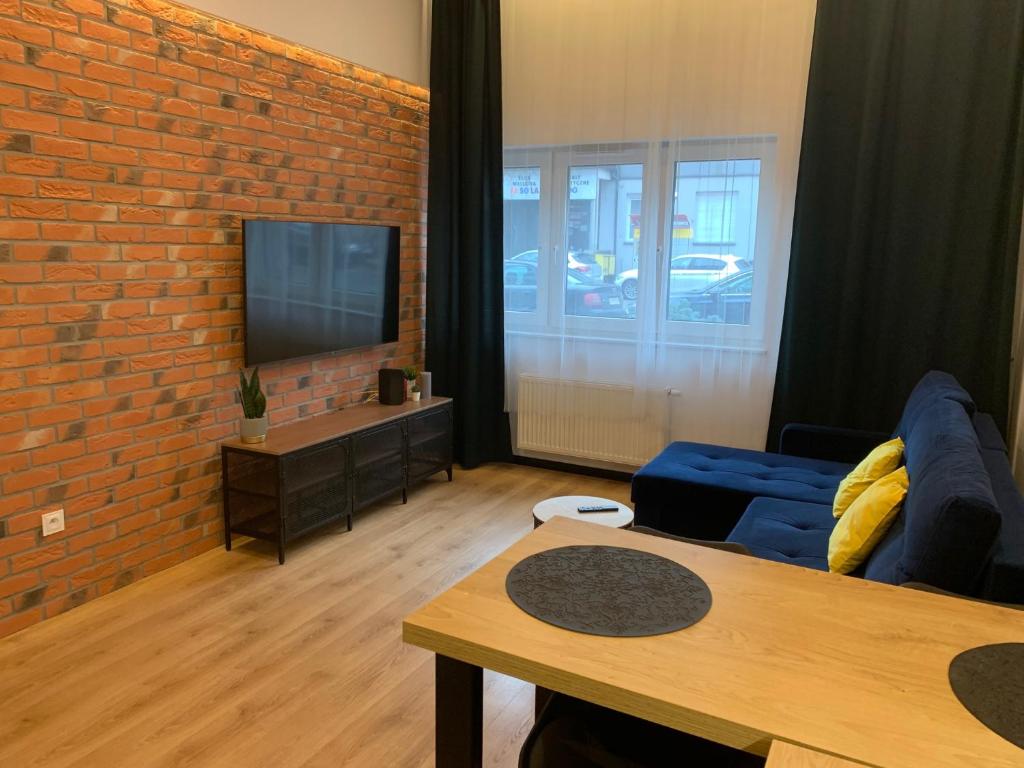 sala de estar con sofá azul y pared de ladrillo en Apartament Kościuszki 13, en Bydgoszcz