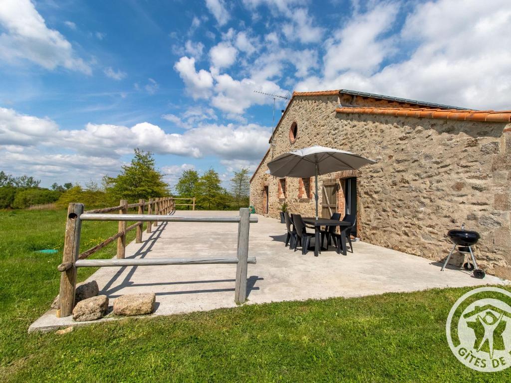 - un bâtiment en pierre avec des tables et un parasol dans l'établissement Gîte Saint-Christophe-du-Bois, 2 pièces, 4 personnes - FR-1-622-33, 