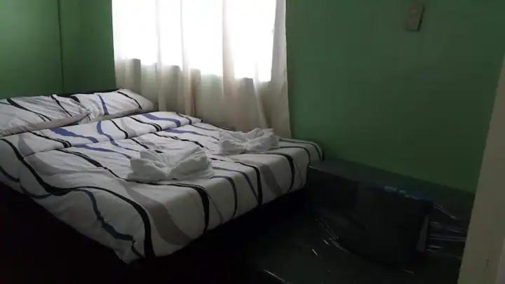 a unmade bed in a green room with a window at Santarem uri del flu in Iloilo City