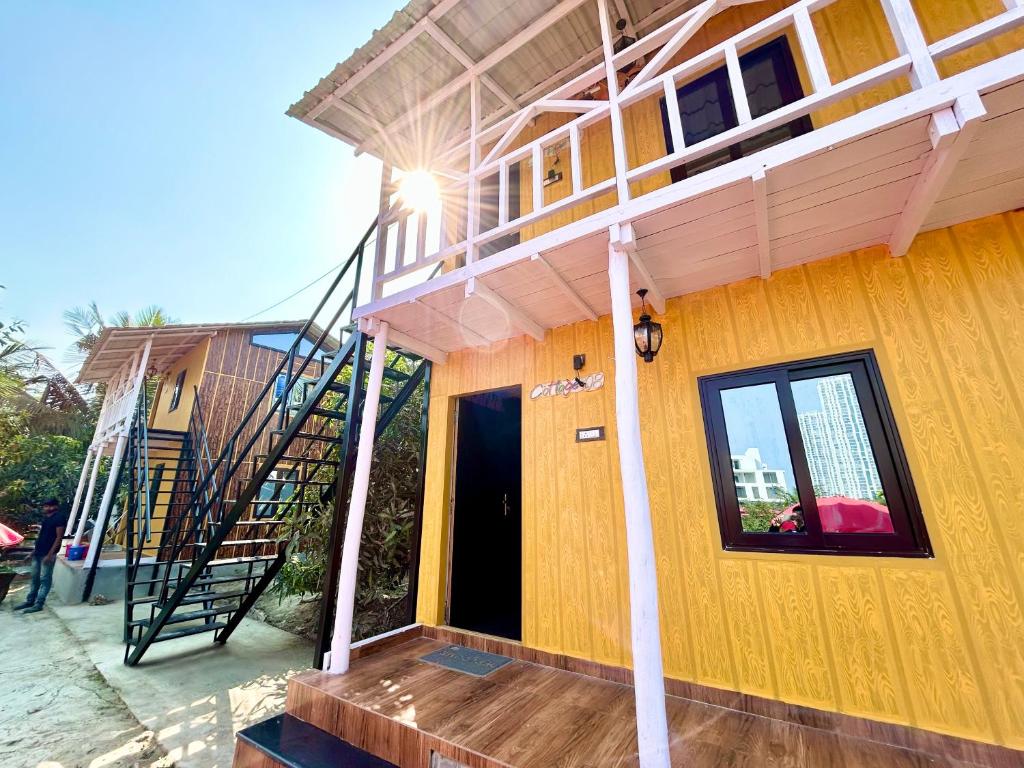 a yellow house with a staircase on the side of it at Palli Bangla Resort, near Ruby Hospital, Anandapur in Kolkata