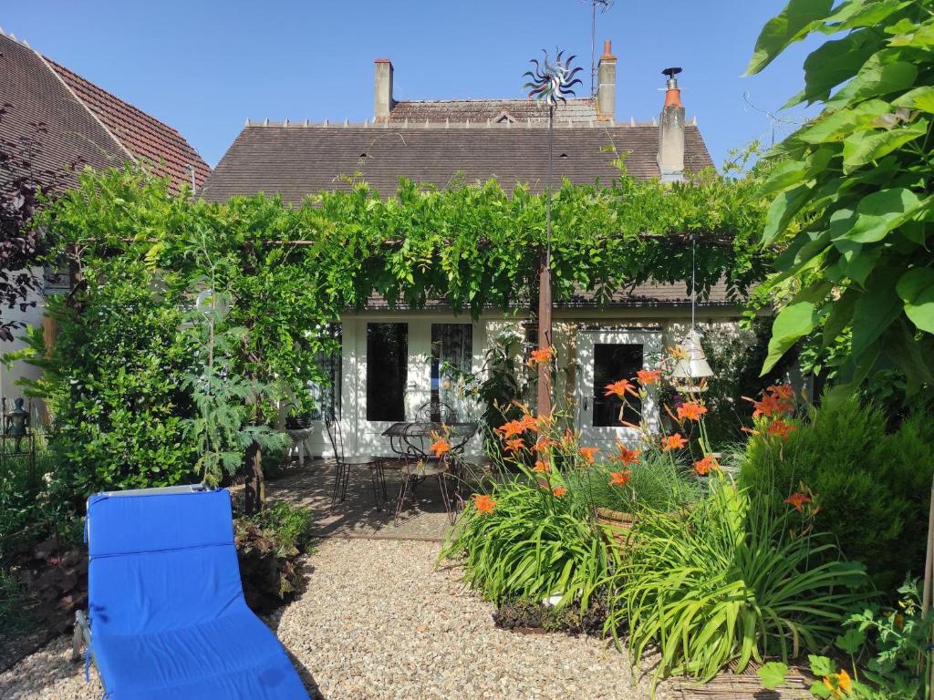 a house with a garden with flowers and a blue chair at Gîte douillet près canal de Berry: Wifi, jardin fleuri, parking, tout compris, lits faits à l'arrivée - FR-1-586-25 in Drevant