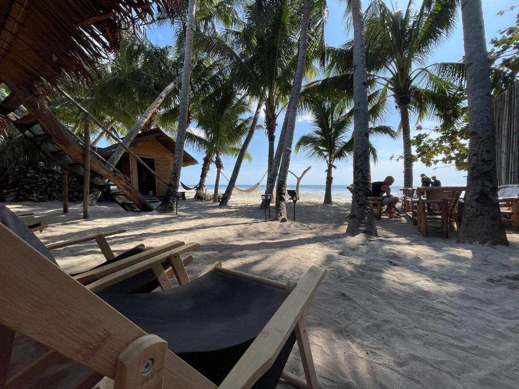 a beach with chairs and palm trees on the beach at Voodoo House in Lalao