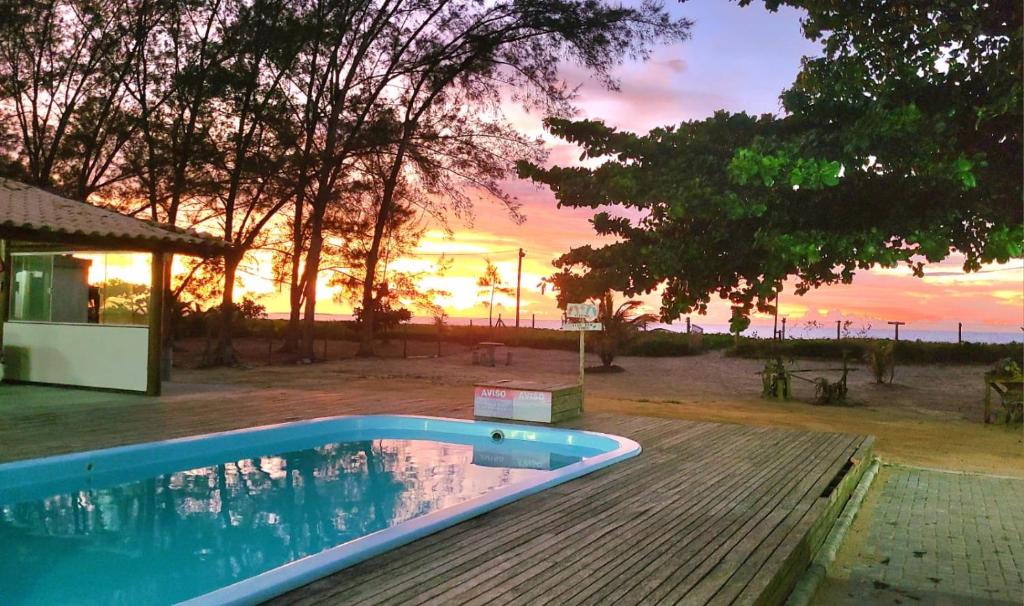 a swimming pool with a sunset in the background at Casa pé na areia - Brandão House in Saco dos Cações