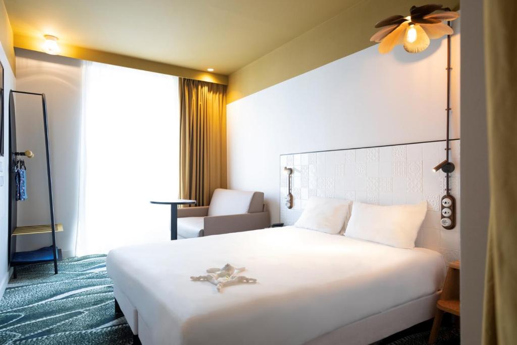 パリにあるハルヴェティアの白い大型ベッドと椅子が備わるホテルルームです。