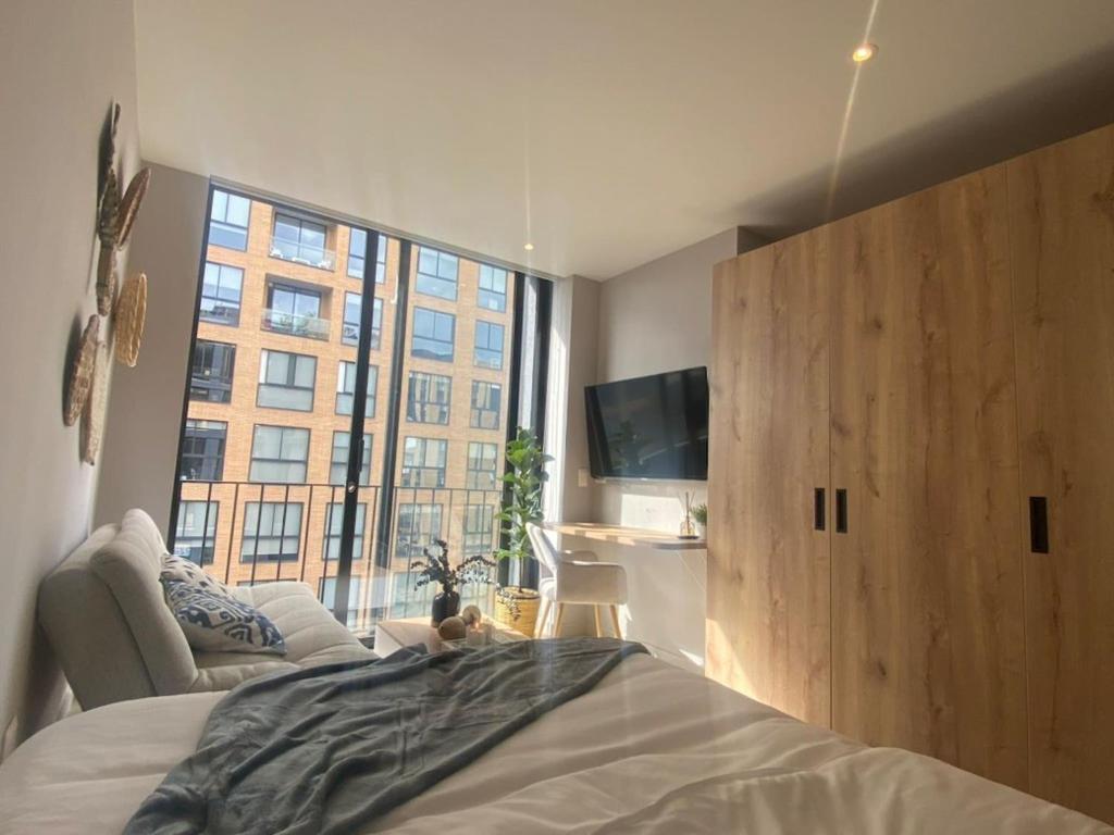 a bedroom with a bed and a large window at Chic downtown loft - near Zona Rosa in Bogotá