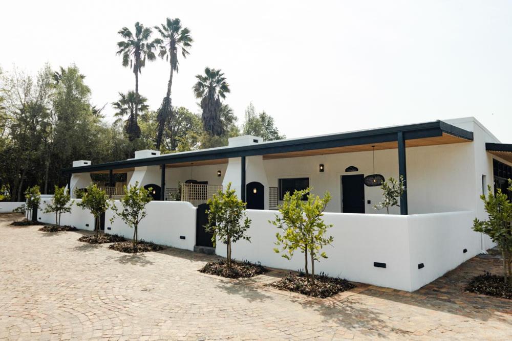un bâtiment blanc avec des arbres devant dans l'établissement Nooitgedacht Guest Farm Cottages, à Kayamnandi