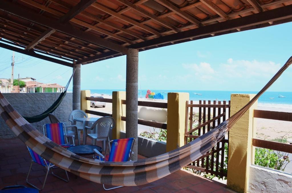eine Hängematte auf einer Terrasse mit Blick auf den Strand in der Unterkunft Casa c WiFi a beira mar na Praia Redonda,Icapui CE in Icapuí