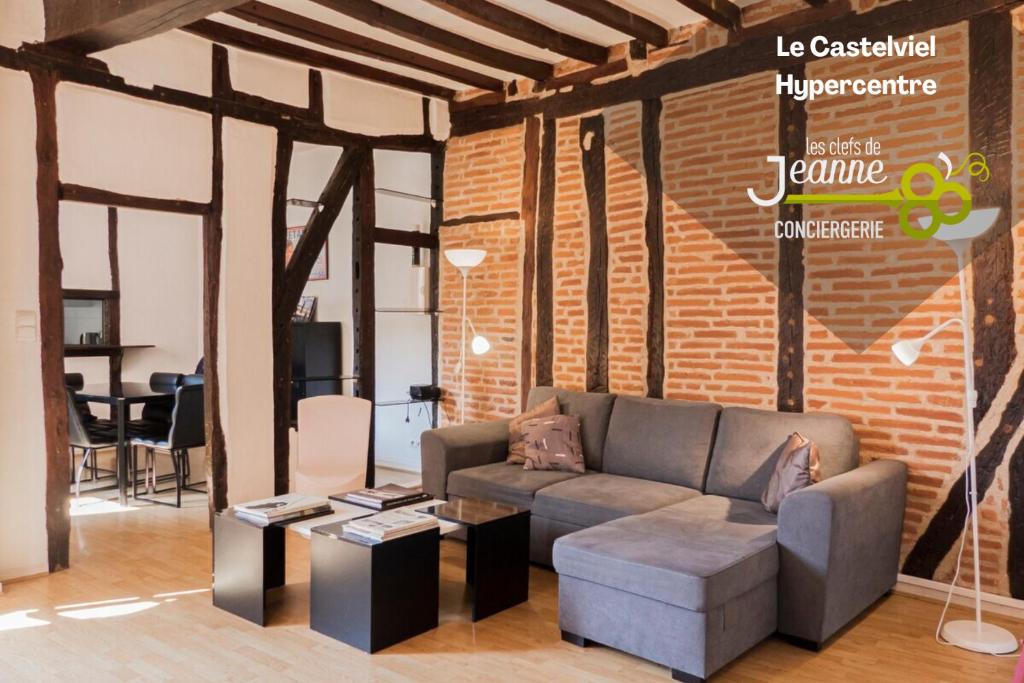 - un salon avec un canapé et un mur en briques dans l'établissement Le Castelviel, à Albi