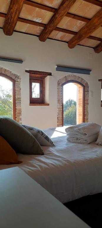 a large bed in a room with two windows at Casa rural Masia Les Apieres. in El Pla de Manlleu