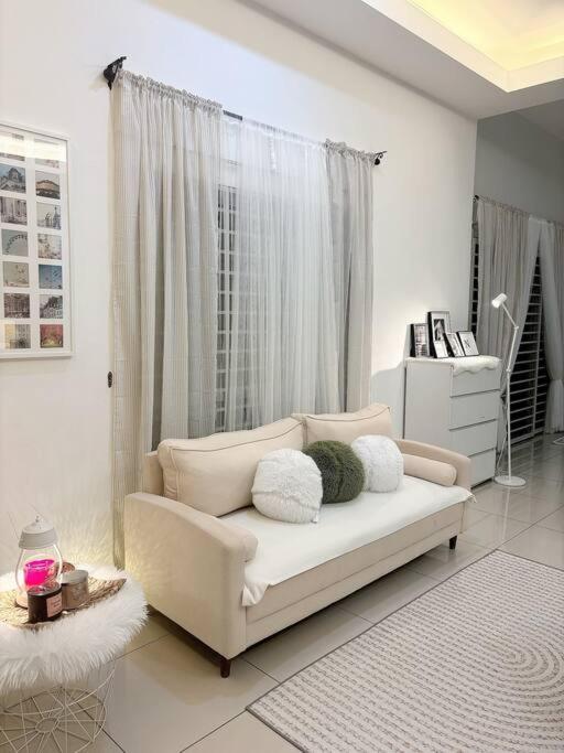 a white living room with a couch and a window at Homestay taiping in Taiping