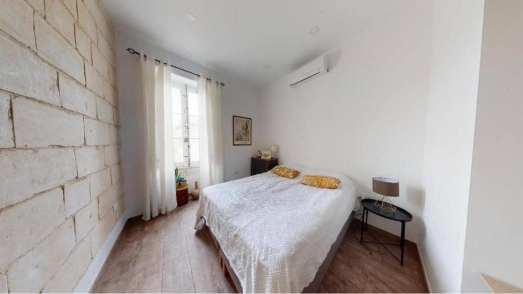 - une chambre blanche avec un lit et un mur en briques dans l'établissement Double bedroom in St Julians in shared house, à San Ġiljan