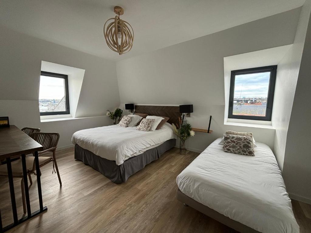 a bedroom with two beds and a table and a dining room at LA TOUR AUX CRABES près de la plage in Dieppe