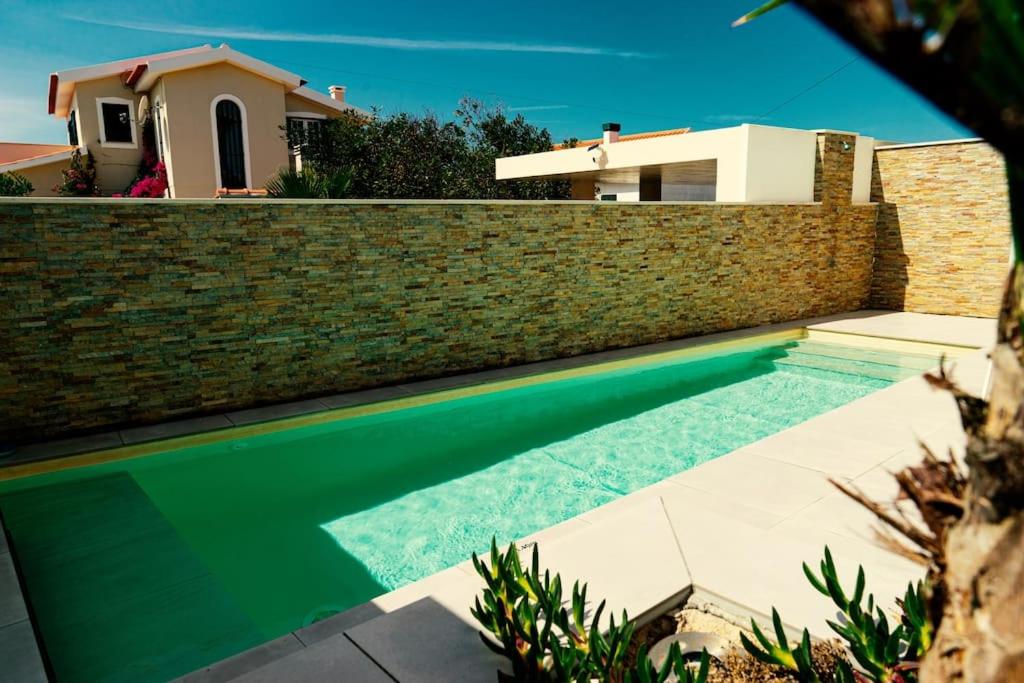a swimming pool in front of a brick wall at Casa da Brisa do Mar in Pataias