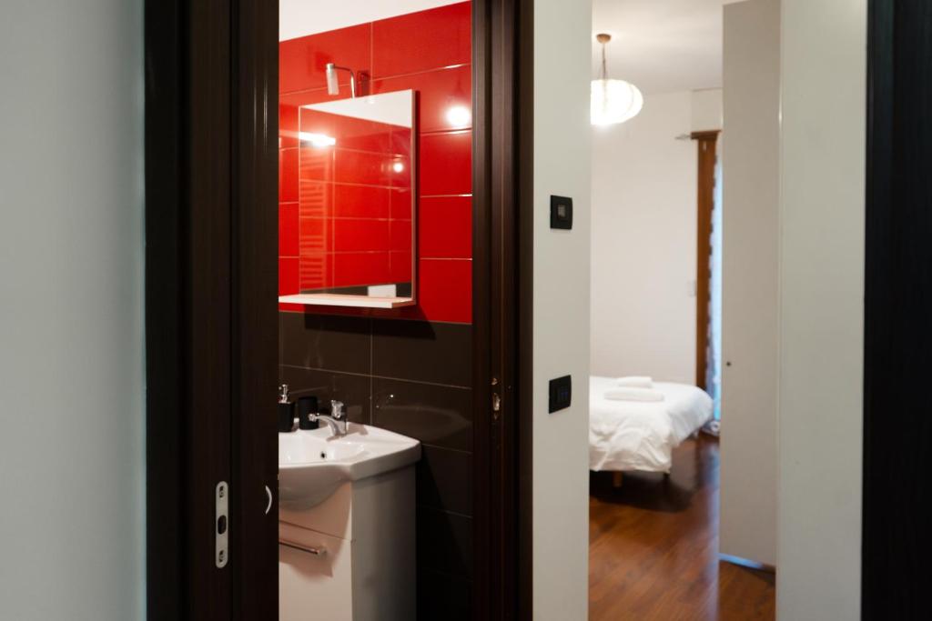 a bathroom with a sink and a red wall at 5min RhoFiera~10minMetro~Parking in Pero